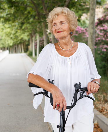 Positive mature woman standing and relaxing after bicycle walkの写真素材