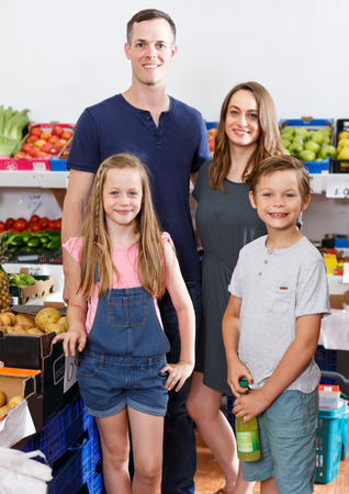 Family with two kids standing near shelves with fruits  in local supermarketの写真素材