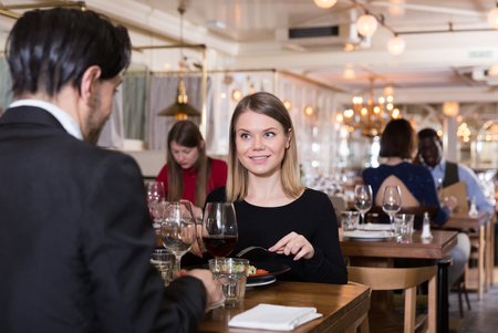Successful business woman with man partner having dinner and drinking red wine in restaurantの写真素材