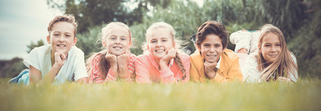Portrait of five kids who are walking and posing lying in the park.の写真素材