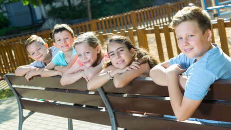 Glad  children sitting on a bench at the playgroundの写真素材