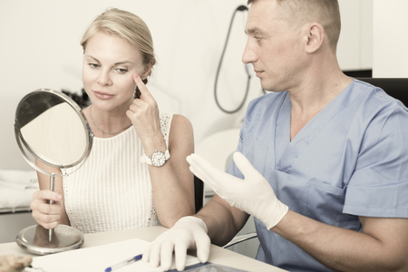 Female client is consultating with doctor before procedure in estetic clinic.の写真素材