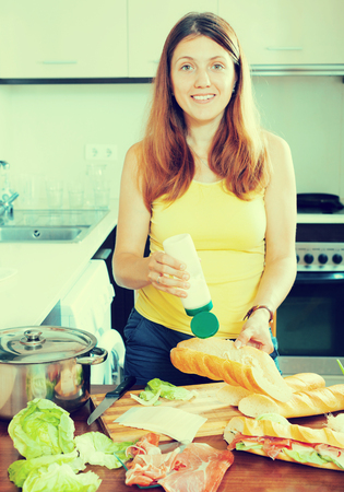 woman cooking  sandwiches with mayonnaise sauce in home  kitchenの写真素材