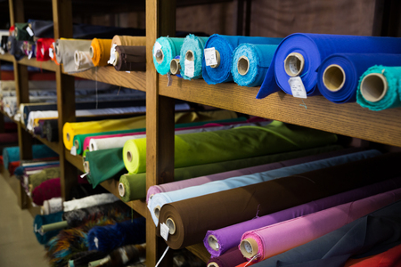 Variety of different fabric bolts exposed on shelves of fabric shopの写真素材