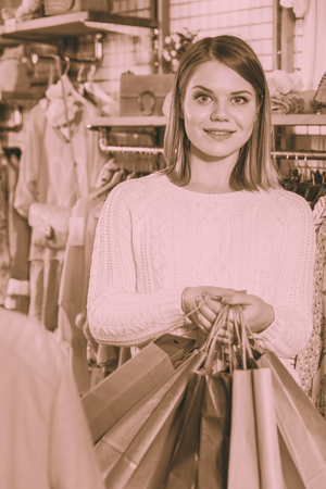 A young woman carrying paper bags with purchases  in a fashion storeの写真素材