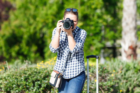 A pretty female traveler strolling with luggage around the city, taking photographsの写真素材