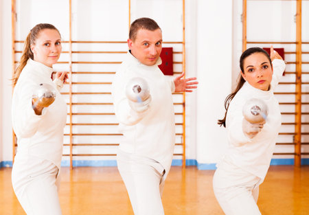 Man and women fencers practicing movements together at fencing workout