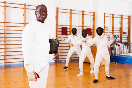 Sporty african american man fencer practicing effective fencing techniques in training roomの写真素材