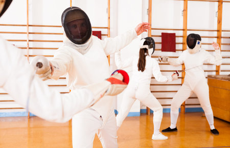 Portrait of athletes at fencing workout, practicing attack movements in duel