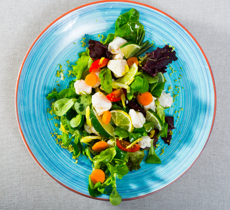 Recipe of salad with pickled merluccius: chop 200g of fish fillet, marinate in lemon juice and black pepper. Serve with lettuce leaves, fresh carrots and lemon slices. Season with oil and balsamicの写真素材