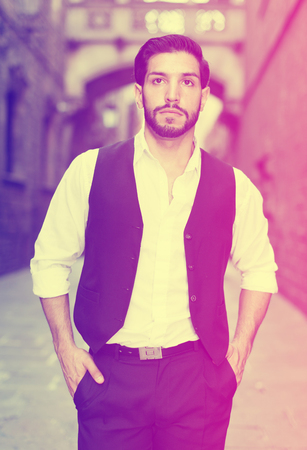 Waist up portrait of confident young man against old stone castleの写真素材