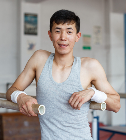 Portrait of smiling young male asian acrobat posing  at sport gymの写真素材