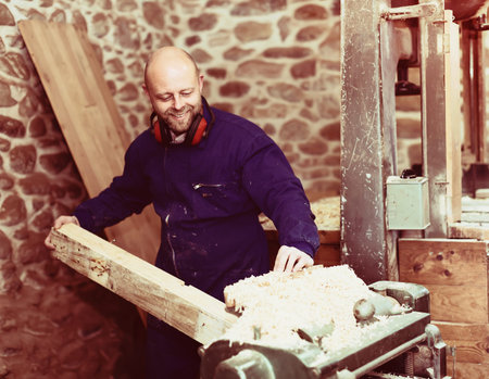 Portrait of smiling professional worker working on a machine at wood workshop