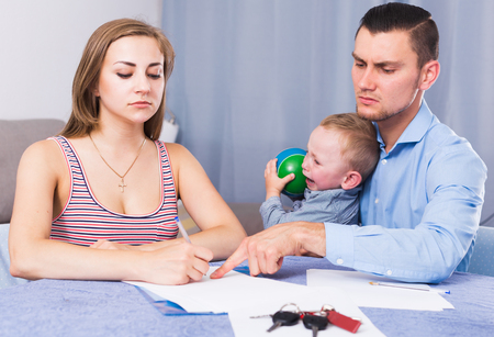 Sad woman with crying boy signing documents about share of propertyの写真素材