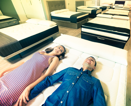 Man and woman choosing mattress in store trying itの写真素材