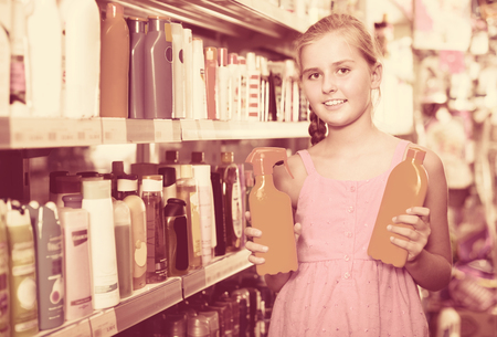 Young girl holding spray and lotion of sun protection at the shopの写真素材