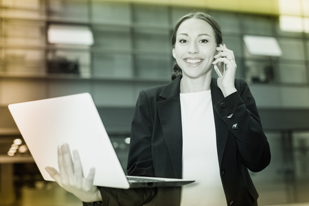 Businesswoman is happy after agreed about the successful transaction by phone outdoors.の写真素材
