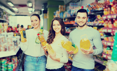 Smiling adults holding seed-oil in plastic packing at shop. Selective focusの写真素材