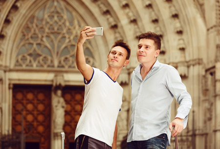 Two gays  with luggage doing selfie at vacationの写真素材