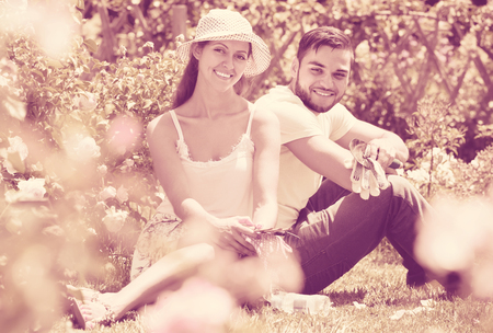Happy young smiling couple resting on the grass after gardeningの写真素材