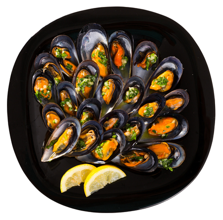 Delicious seafood mussels with parsley and garlic sauce on plate. Isolated over white backgroundの写真素材