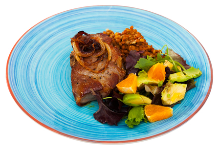 Baked pork shank with lentils and healthy summer salad of avocado, greens and orange. Isolated over white backgroundの写真素材