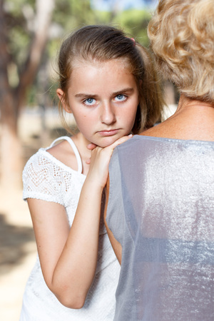 Tired teen girl hug grandmother in summer green park at sunny day outdoorの写真素材
