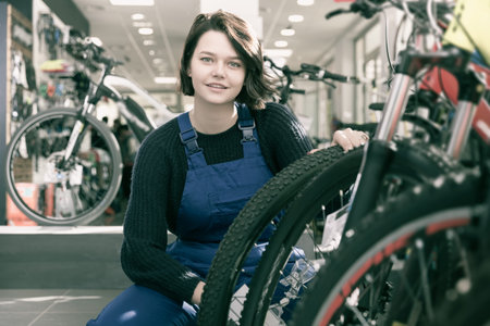 Portrait of young professional woman holding cycle frame in bicycle shop