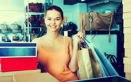 Positive  happy glad teenager girl shopping in store with bags and accessoriesの写真素材