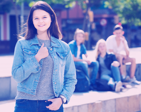 Portrait of glad american teenager girl standing aside from friends outdoorsの写真素材