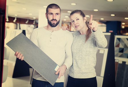 Young family couple standing with sample of ceramic tile  in shopの写真素材