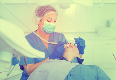 dentist professional filling teeth for man patient sitting in medical chairの写真素材