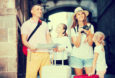 Smiling parents with  children using map and photographing sights during their vacationの写真素材
