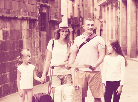 positive  english parents with two kids traveling together searching location on paper mapの写真素材