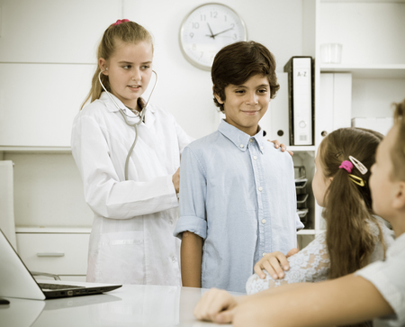 Young female doctor in uniform leading medical appointment with childrenの写真素材