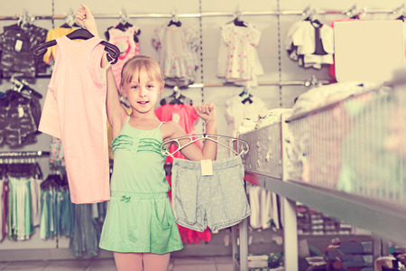 Portrait of happy spanish girl choosing colored dress and wear in the shopの写真素材