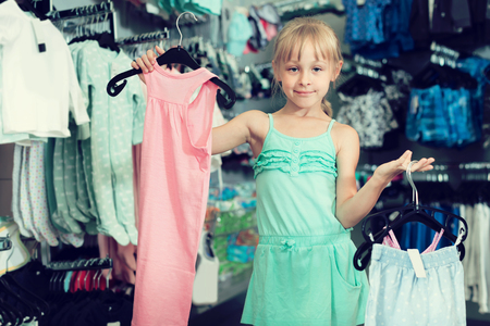 Portrait of happy girl choosing colored dress and wear in the shopの写真素材