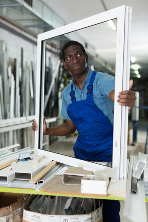 Adult man master is looking on modern window frame in the workshop.の写真素材