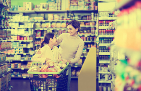 Attractive woman with teenage daughter restocking for family in supermarketの写真素材