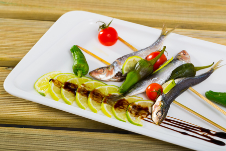 Grilled sardines with fresh vegetables served with lime and balsamic pasta on plateの写真素材