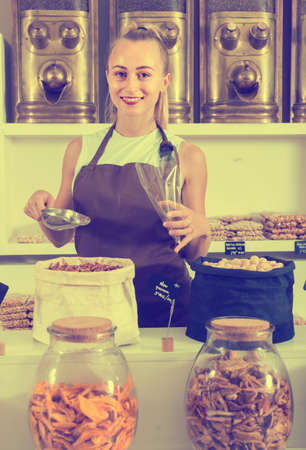 Girl seller is demonstraiting Pecana in bag and on the plate is written in Catalan in the shop.の写真素材