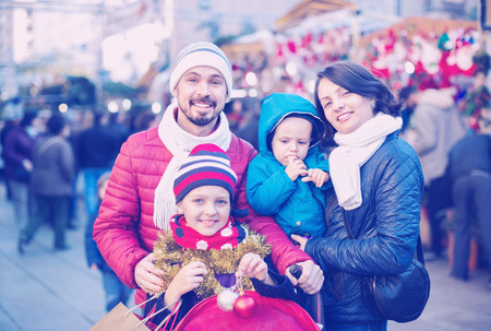 Ordinary  glad parents with kids choosing X-mas decorations in marketの写真素材