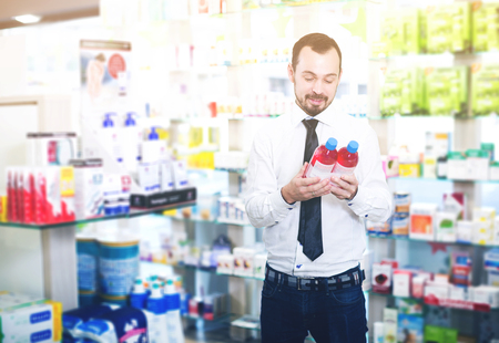 Positive young customer searching for reliable drug in pharmacyの写真素材