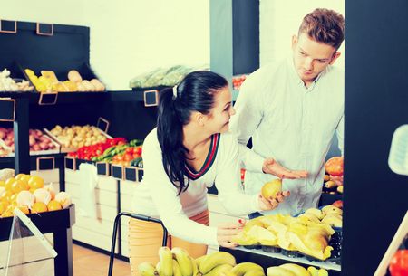 Adult couple deciding on fruits in grocery shopの写真素材