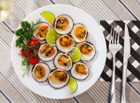 Image of a  baked in oven with sauce dog cockle with lemon and fresh greens