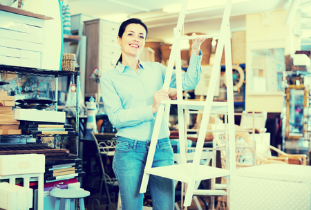 Woman standing with stepladder in decoration and furniture storeの写真素材