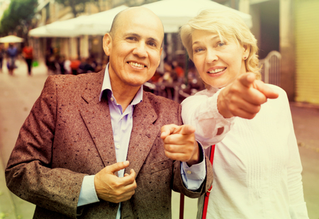 glad senior couple taking promenade and point their fingers outdoorsの写真素材