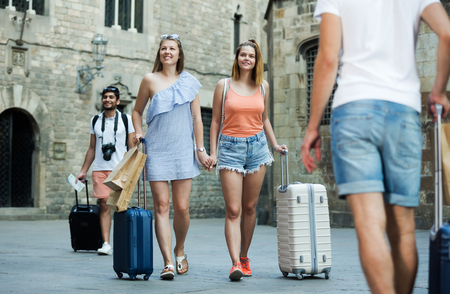 portrait of happy adult female couple tourists taking walk in town together on summer dayの写真素材