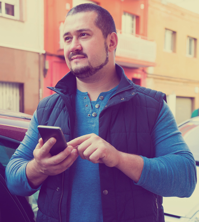 man in city with phone in his hands outdoorsの写真素材