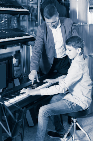 Father and son are looking for a suitable keyboard model in the music storeの写真素材
